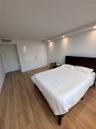 Wood-finish flooring, high-gloss built-in cabinetry, and recessed lighting in a coffered ceiling element