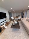 Living area featuring wood-finish flooring, recessed lighting, and a wall-mounted shelving unit