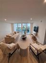 Living area featuring wood-finish flooring, recessed lighting, and floor-to-ceiling glass doors providing balcony access