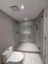 Walk-in shower featuring a frameless glass enclosure, neutral large-format tile wall surrounds, built-in recessed wall niche, and integrated shower fi