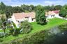 Waterfront property featuring a grass lawn, tile roof, and mature perimeter trees