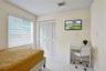 Neutral-toned interior featuring large-format tile flooring, louvered bi-fold closet doors, and adjustable window blinds