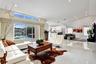 Open-concept living area featuring vaulted ceilings, large-format tile flooring, recessed lighting, and expansive sliding glass doors with clerestory 