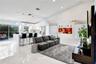 Open-concept interior featuring vaulted ceilings, recessed lighting, white cabinetry with integrated appliances, a kitchen island with stone-finish co