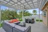 Covered patio featuring a white pergola, ceiling fan, concrete flooring, and solid white fencing