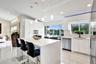 Modern kitchen featuring high-gloss cabinetry, a central island with a stone countertop, built-in stainless steel appliances, polished tile flooring, 