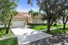 Single-story residence featuring a tiled roof, paver driveway, two-car garage, and established landscaping