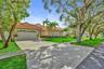 Single-story residence featuring a tile roof, paver driveway, two-car garage, and established landscaping