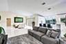 Open-concept interior featuring vaulted ceilings, high-gloss cabinetry, large-format tile flooring, a kitchen island with pendant lighting, and cleres