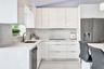 Modern kitchen featuring high-gloss cabinetry, stone-finish countertops, full-height backsplash, undermount sink with a gooseneck faucet, and integrat