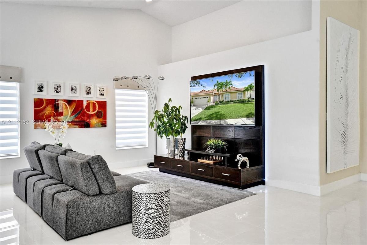 High-ceiling interior space featuring polished tile flooring, tiered built-in dark wood cabinetry, and window treatments with horizontal blinds