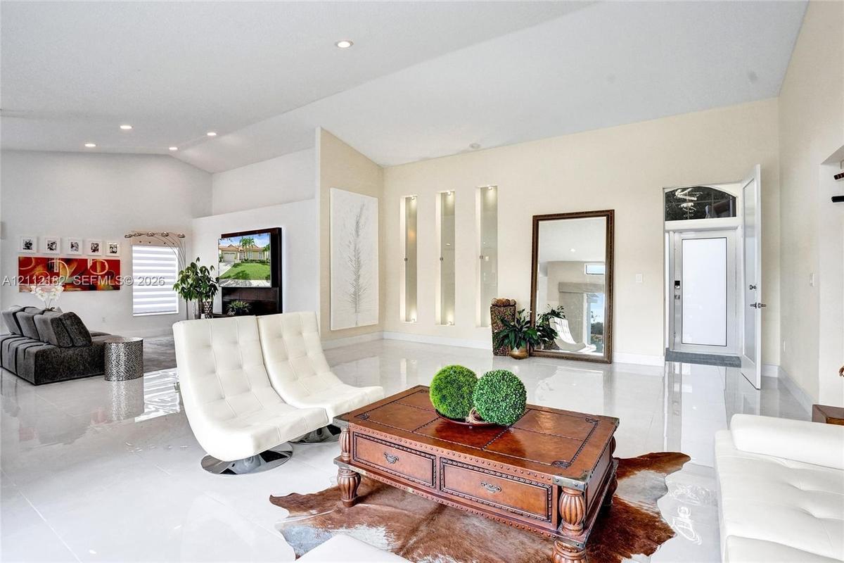 Open-concept interior featuring vaulted ceilings, recessed lighting, high-gloss tile flooring, and integrated wall niches