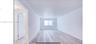 Neutral interior space featuring wood-finish flooring, a rectangular window, and a white door with a metal handle