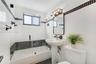 Bathroom featuring a pedestal sink, a glass-enclosed shower-tub combination, and black-and-white tile accents throughout