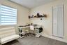 Wood-finish flooring, dual-pane window with zebra-style roller shades, and white louvered-style closet doors