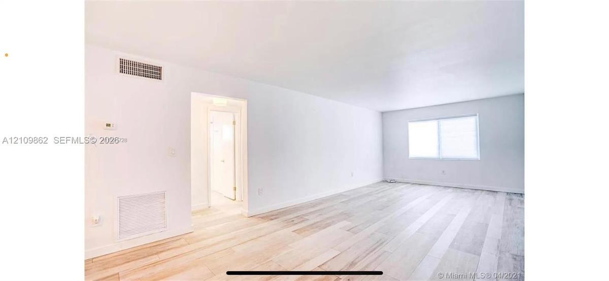 Open-concept interior featuring light wood-finish flooring, smooth ceilings, and a large horizontal window