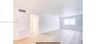 Open-concept interior featuring light wood-finish flooring, smooth ceilings, and a large horizontal window