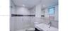 Modern bathroom featuring a glass-enclosed walk-in shower with stone tile walls, a decorative mosaic tile accent strip, a square rainfall showerhead, 