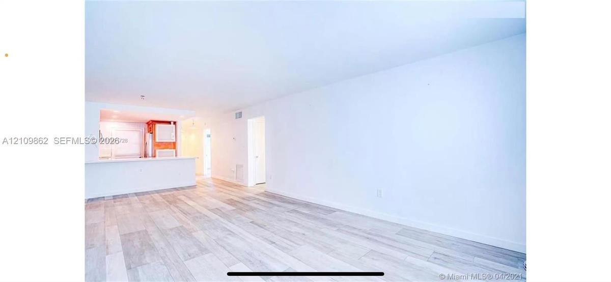 Open-concept interior featuring wood-finish flooring and a kitchen pass-through counter
