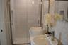 Walk-in shower with horizontal tile surround and integrated wall niche, featuring a dual-sink vanity with circular vessel sinks, polished chrome fauce