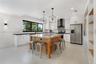 Kitchen featuring white shaker-style cabinetry, center island with stone countertop, geometric pendant lighting, patterned tile backsplash, and stainl