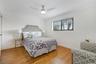 Room featuring wood-finish flooring, vertical plank wall detailing, crown molding, and a ceiling fan with integrated lighting