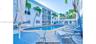 Outdoor community pool featuring a concrete deck, screen-enclosed balconies, and mature palm trees