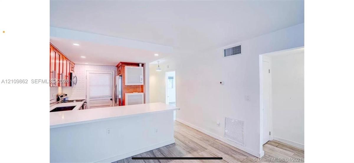 Kitchen featuring wood-finish cabinetry, white countertop, white subway tile backsplash, and wood-finish flooring