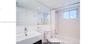 Bathroom featuring a rectangular vessel sink with a chrome faucet, large wall-mounted mirror, white elongated toilet, and a combination tub and shower