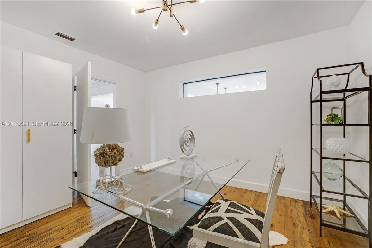Wood-finish flooring, built-in floor-to-ceiling cabinetry, horizontal clerestory window, and multi-arm chandelier