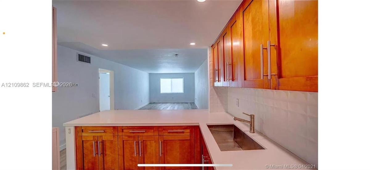 Kitchen featuring warm-tone wood cabinetry, white countertops, a stainless steel undermount sink, a metallic finish faucet, and recessed lighting