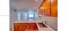 Kitchen featuring warm-tone wood cabinetry, white countertops, a stainless steel undermount sink, a metallic finish faucet, and recessed lighting