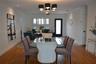Wood-finish flooring, multi-light chandelier with black shades, white plantation shutters, and a high-contrast black exterior door frame