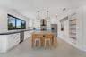 Kitchen featuring a center island with wood-finish cabinetry, stone countertop, geometric metal pendant lighting, patterned tile backsplash, and built