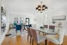 Open-concept interior featuring wood-finish flooring, multi-light chandelier, crown molding, recessed lighting, and multi-pane window with shutter acc