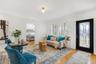 Wood-finish flooring, white walls, multi-pane casement windows with plantation shutters, globe-style ceiling lighting, and a black front door featurin