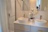 Double vanity featuring a stone-composite countertop, dual circular vessel sinks, gold-tone hardware, and a glass-enclosed shower