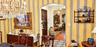Arched entryway featuring a multi-tiered crystal chandelier, striped wallpaper, built-in shelving, and patterned tile flooring