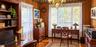 Wood-paneled walls with decorative crown molding, floor-to-ceiling built-in shelving, hardwood flooring, and a multi-arm chandelier