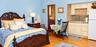 Wood-finish flooring, kitchenette featuring shaker-style cabinetry, stone-style tile backsplash, and light-toned countertop