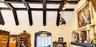 Vaulted ceiling featuring dark-finished exposed beams, textured wall finish, and archway architectural detailing