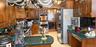 Kitchen featuring raised-panel wood cabinetry, integrated double wall ovens, a gas cooktop, solid-surface countertops, and a ceiling-mounted pot rack