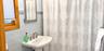 Wall-mounted pedestal sink with polished metal faucet, light blue subway tile backsplash, glass mosaic tile accent border, and natural wood-finish win