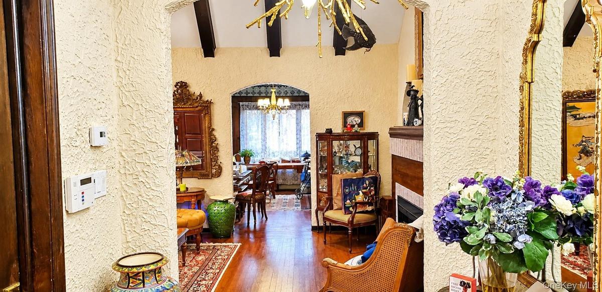 Arched entryways featuring textured walls, dark wood-finish ceiling beams, and hardwood flooring
