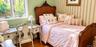 Bedroom featuring wood-finish flooring, multi-pane window, and vertical striped wallpaper accent wall