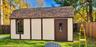 Exterior storage structure featuring asphalt shingle roofing, paneled siding, a single-entry door with a glass inset, and an arched window
