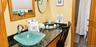 Bathroom vanity featuring a glass vessel sink, dark stone countertop, wood cabinetry, and a chrome faucet