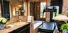 Stone-surfaced vanity with integrated sink, stone wall cladding, built-in wooden cabinetry, multi-paned glass doors, and large wall-mounted mirror
