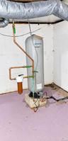 Water pressure tank featuring copper piping, an inline filtration system, and a concrete base