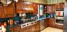 Custom wood cabinetry with an integrated range hood, professional-grade gas cooktop, double wall ovens, stainless steel dishwasher, and solid-surface 